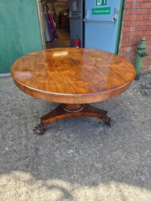 fig 1. A circular Regency rosewood breakfast table featuring a figured veneer top resting on a central pedestal column with a triform base and carved feet.