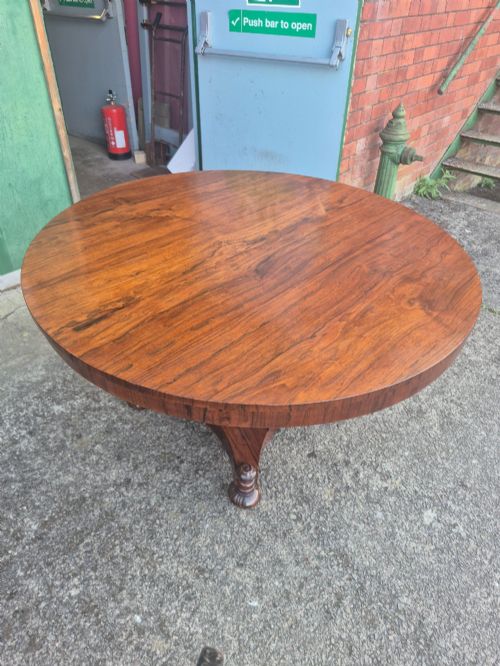 fig 1. A circular Regency rosewood breakfast table featuring a figured veneer top, carved acanthus leaf pedestal column, and a concaved quadform base.