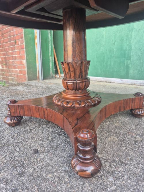 fig 5. A circular Regency rosewood breakfast table featuring a figured veneer top, carved acanthus leaf pedestal column, and a concaved quadform base.