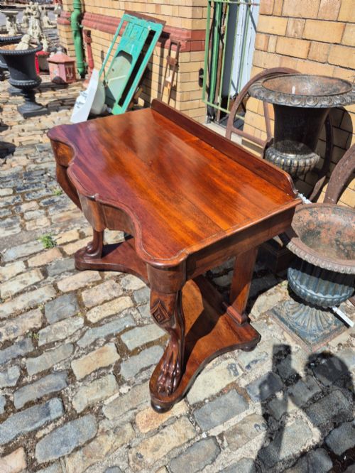 fig 2. An early Victorian mahogany console table with a shaped serpentine top, carved cabriole front legs, and an undertier shelf resting on a plinth base.