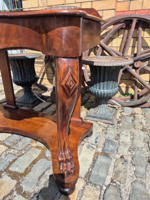 fig 4. An early Victorian mahogany console table with a shaped serpentine top, carved cabriole front legs, and an undertier shelf resting on a plinth base.