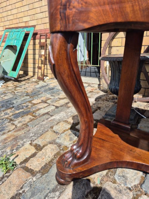 fig 5. An early Victorian mahogany console table with a shaped serpentine top, carved cabriole front legs, and an undertier shelf resting on a plinth base.