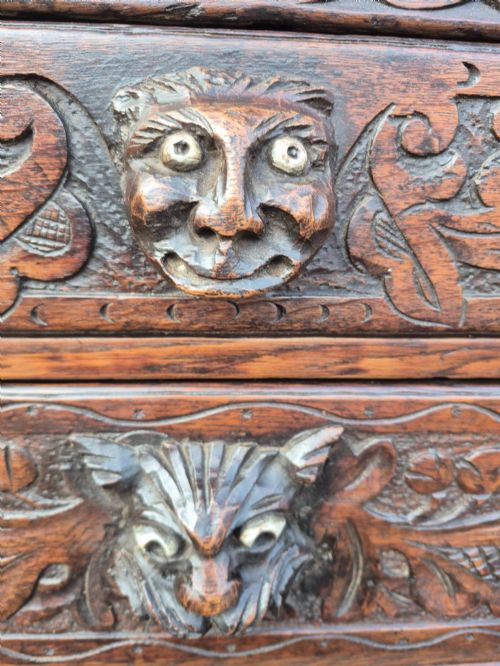 fig 2. A nineteenth-century dark oak chest of drawers featuring hand-carved grotesque Green Man face masks and elaborate foliate scrollwork across the front.