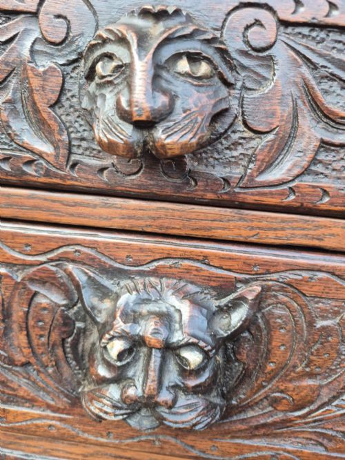 fig 3. A nineteenth-century dark oak chest of drawers featuring hand-carved grotesque Green Man face masks and elaborate foliate scrollwork across the front.