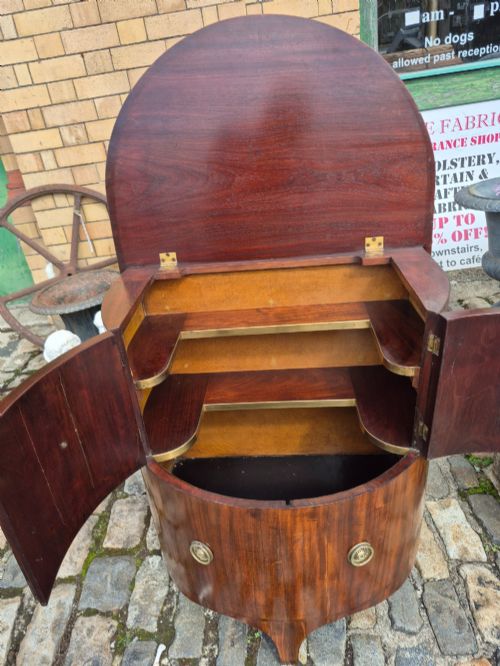 fig 3. A small semi-circular mahogany cocktail cabinet featuring flame veneer panels and circular brass patera handles.