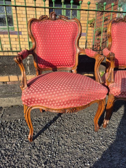 fig 2. A pair of French carved walnut armchairs upholstered in patterned red fabric with cabriole legs and scrolled cresting.