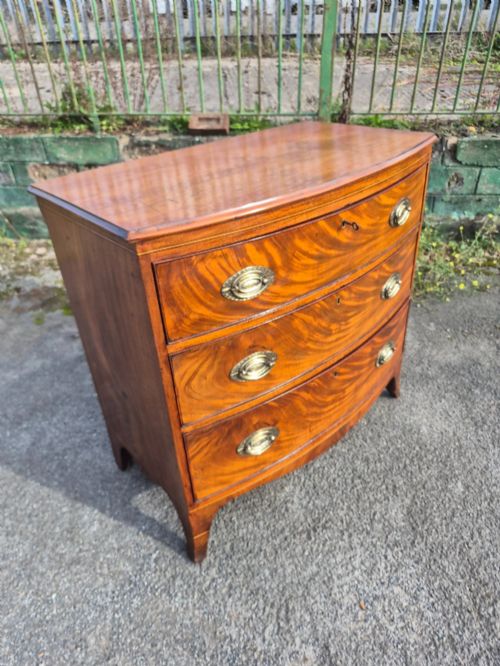 fig 2. A Regency period bowfront chest of drawers crafted from flame mahogany veneer with three drawers and brass oval handles.