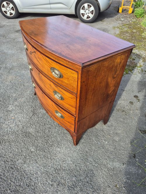 fig 3. A Regency period bowfront chest of drawers crafted from flame mahogany veneer with three drawers and brass oval handles.