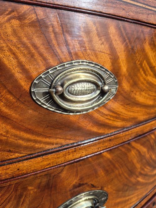 fig 4. A Regency period bowfront chest of drawers crafted from flame mahogany veneer with three drawers and brass oval handles.