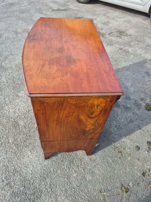 fig 6. A Regency period bowfront chest of drawers crafted from flame mahogany veneer with three drawers and brass oval handles.