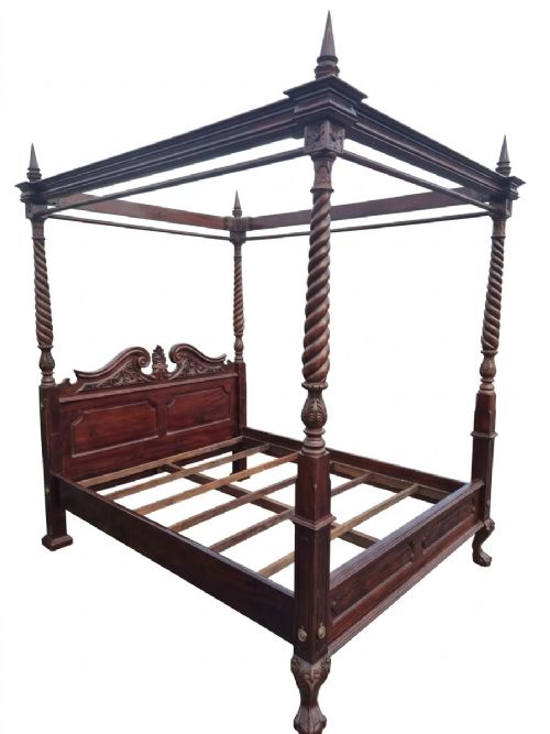 fig 2. A dark mahogany four-poster bed frame featuring four spiral barley-twist posts topped with finials, a carved headboard, and claw-and-ball feet.