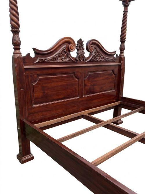fig 3. A dark mahogany four-poster bed frame featuring four spiral barley-twist posts topped with finials, a carved headboard, and claw-and-ball feet.