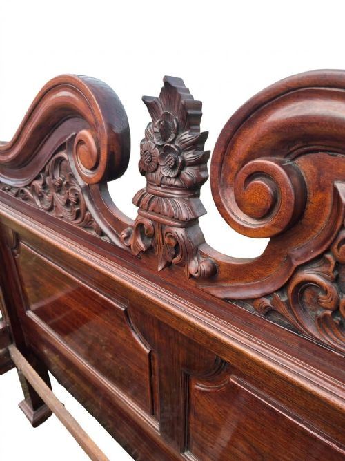 fig 4. A dark mahogany four-poster bed frame featuring four spiral barley-twist posts topped with finials, a carved headboard, and claw-and-ball feet.
