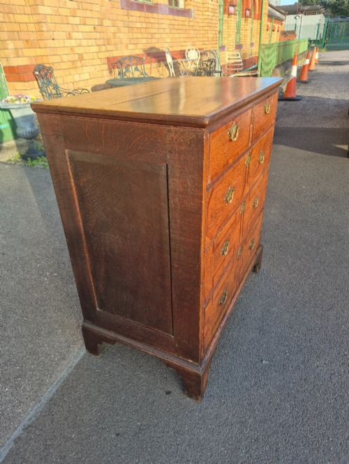 fig 3. An Early Georgian oak and walnut chest of drawers featuring geometric wood banding, engraved brass handles, and bracket feet.