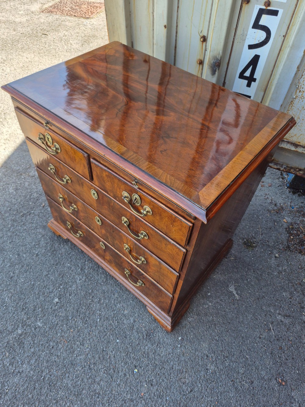 An 18th-century Georgian walnut bachelors chest featuring a brushing slide, four graduated drawers with brass handles, and bracket feet. View II