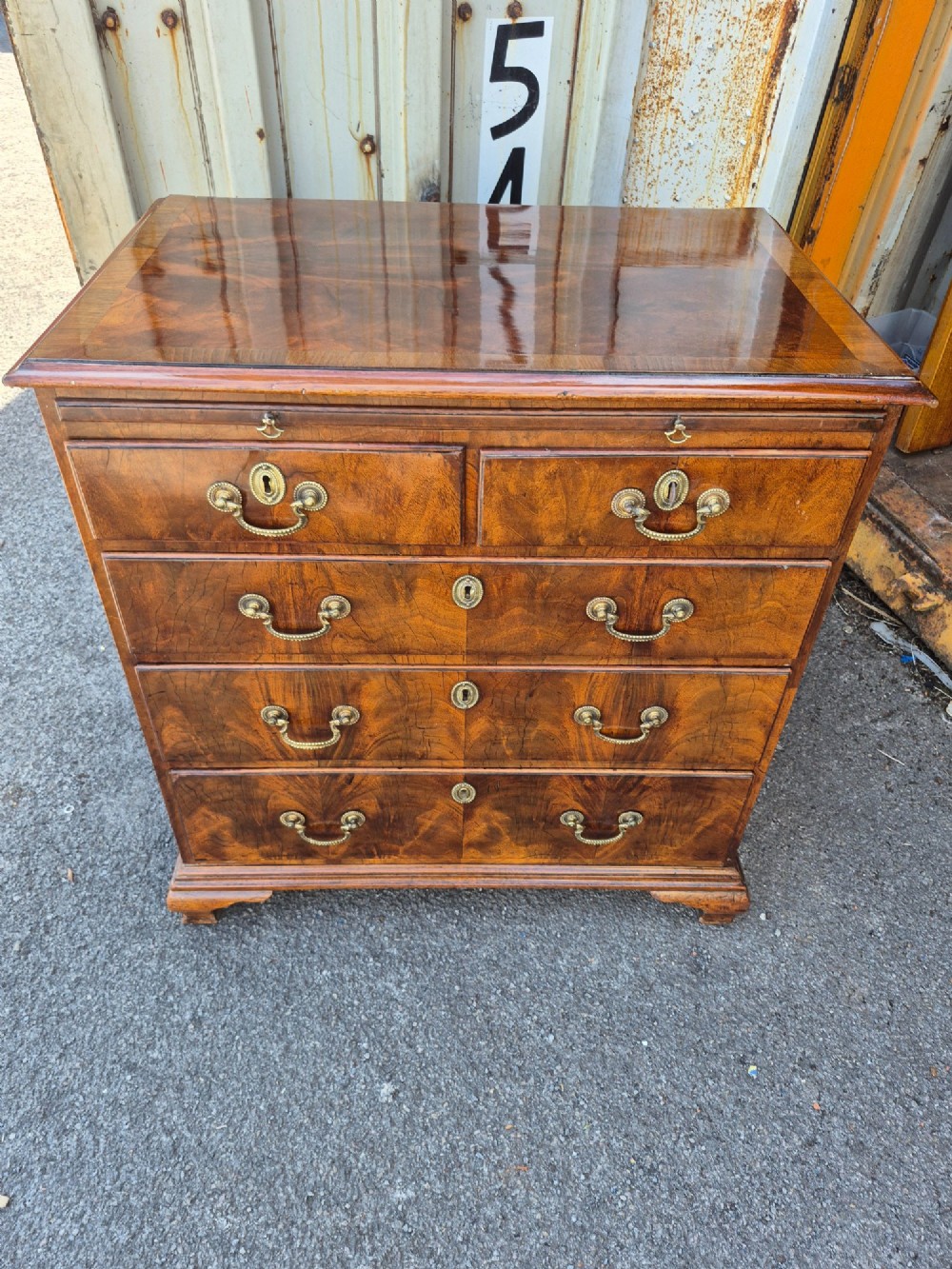 An 18th-century Georgian walnut bachelors chest featuring a brushing slide, four graduated drawers with brass handles, and bracket feet. View IV