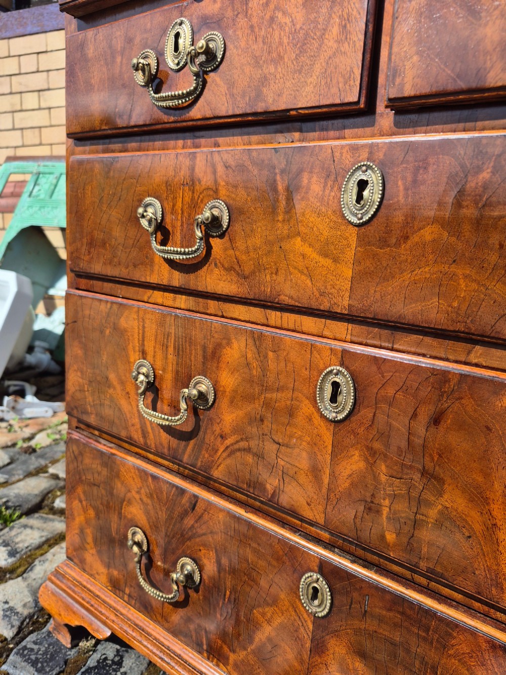 An 18th-century Georgian walnut bachelors chest featuring a brushing slide, four graduated drawers with brass handles, and bracket feet. View VII