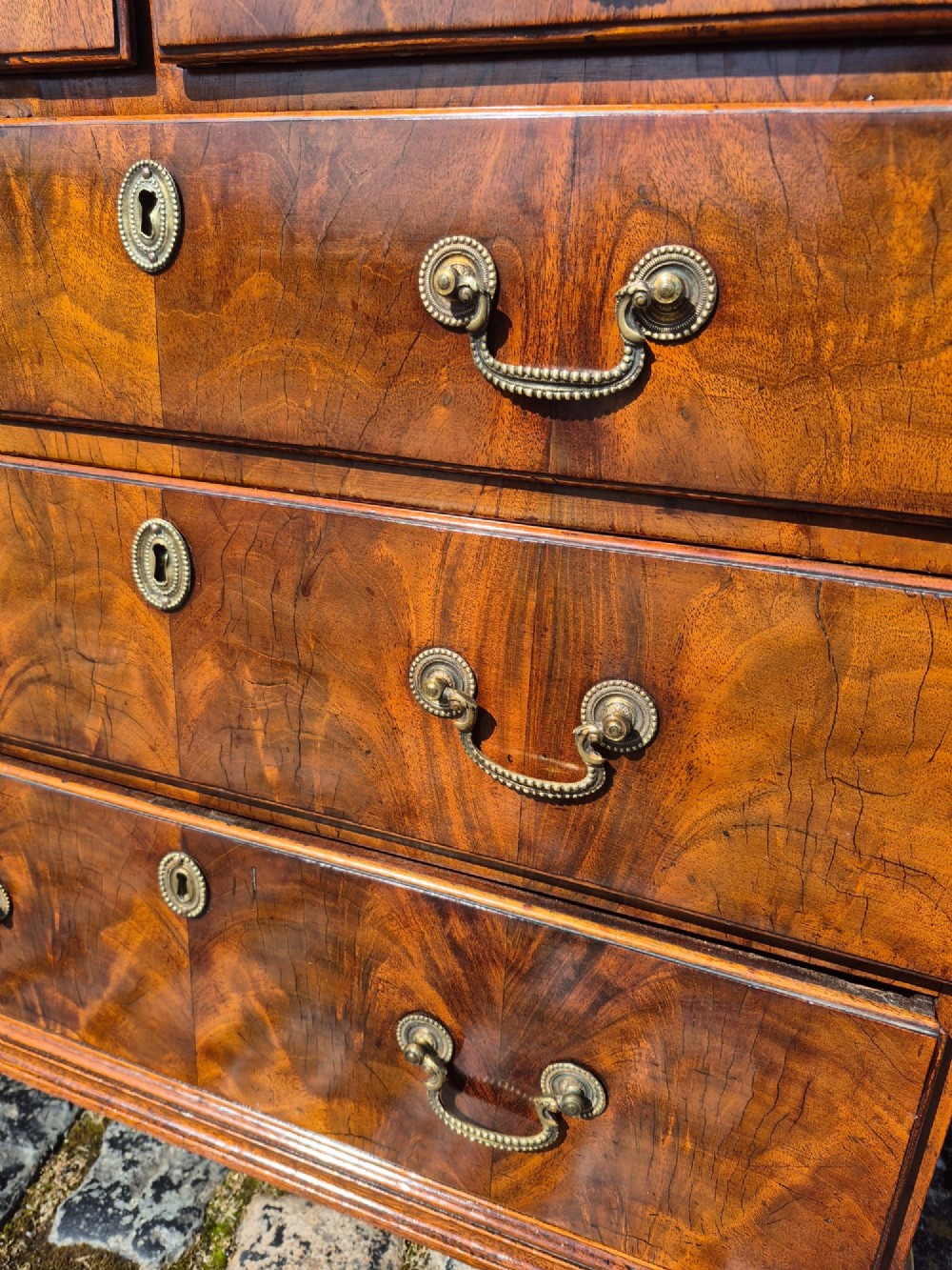 An 18th-century Georgian walnut bachelors chest featuring a brushing slide, four graduated drawers with brass handles, and bracket feet. View VIII