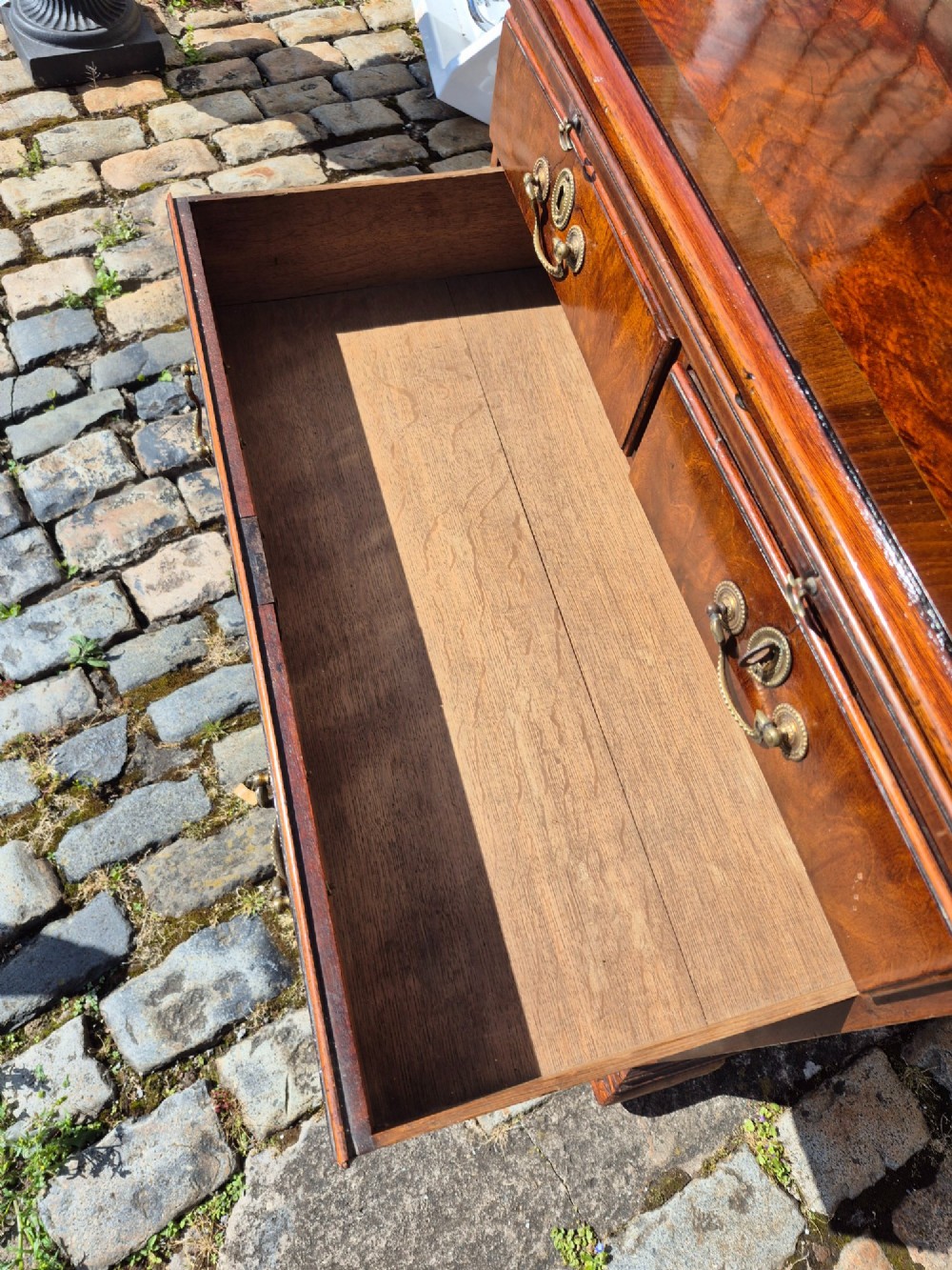 An 18th-century Georgian walnut bachelors chest featuring a brushing slide, four graduated drawers with brass handles, and bracket feet. View IX