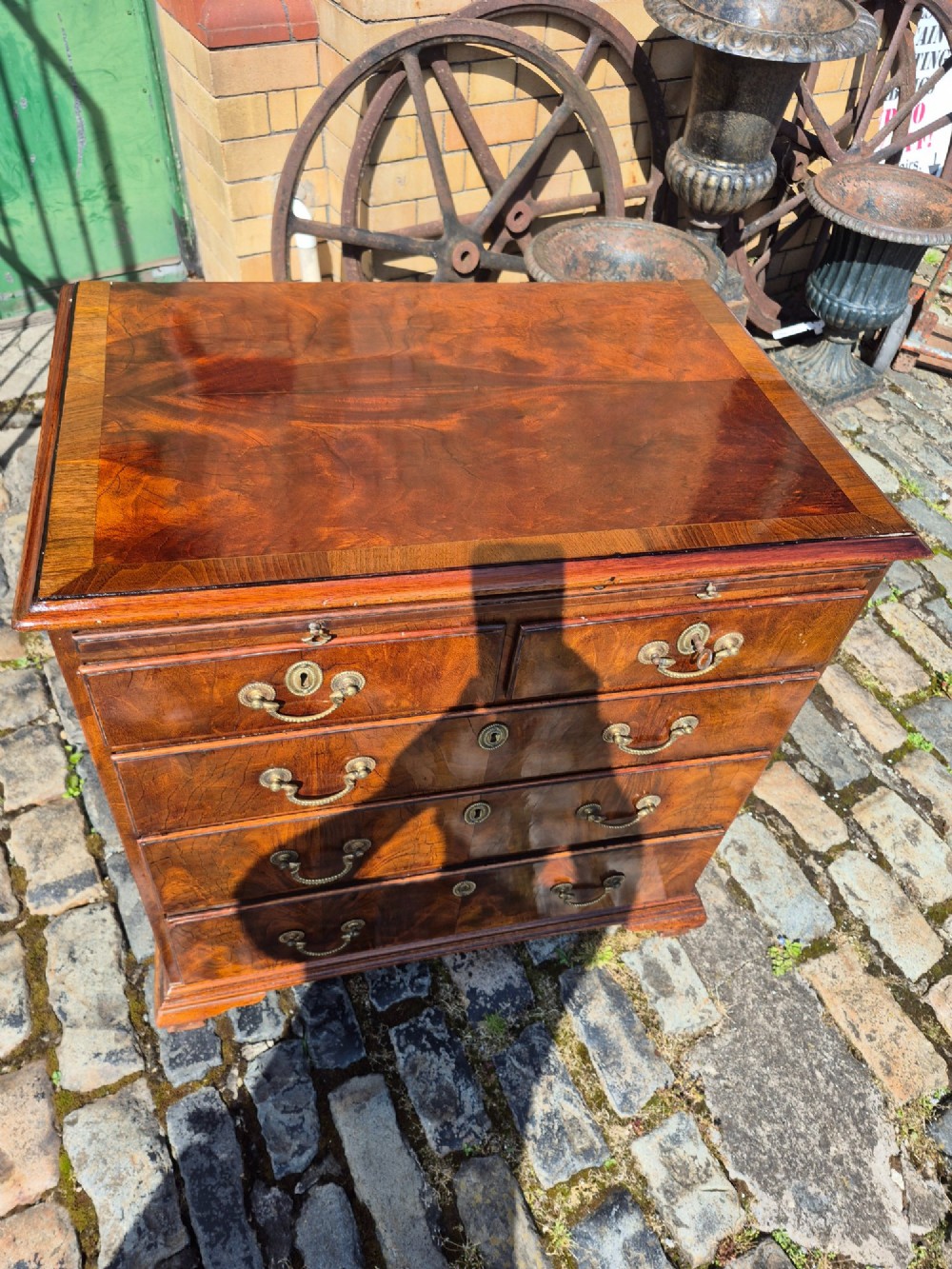 An 18th-century Georgian walnut bachelors chest featuring a brushing slide, four graduated drawers with brass handles, and bracket feet. View XI