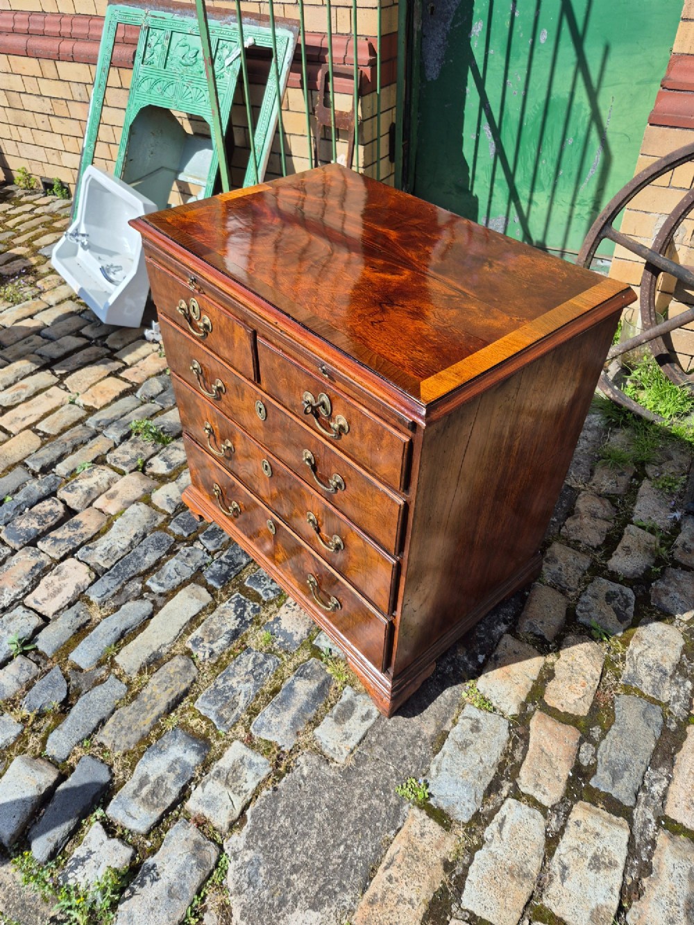 An 18th-century Georgian walnut bachelors chest featuring a brushing slide, four graduated drawers with brass handles, and bracket feet. View XIII