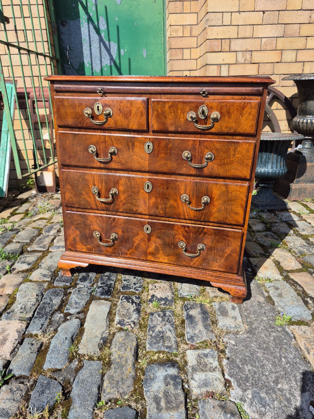 An 18th-century Georgian walnut bachelors chest featuring a brushing slide, four graduated drawers with brass handles, and bracket feet. View XIV
