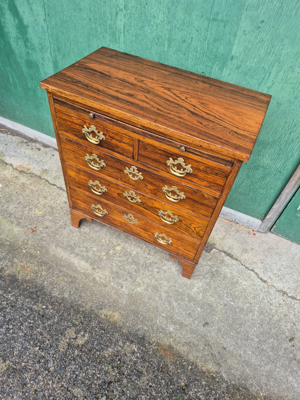 A small rosewood chest of drawers featuring brass handles, bracket feet, and a pull-out brushing slide. View II