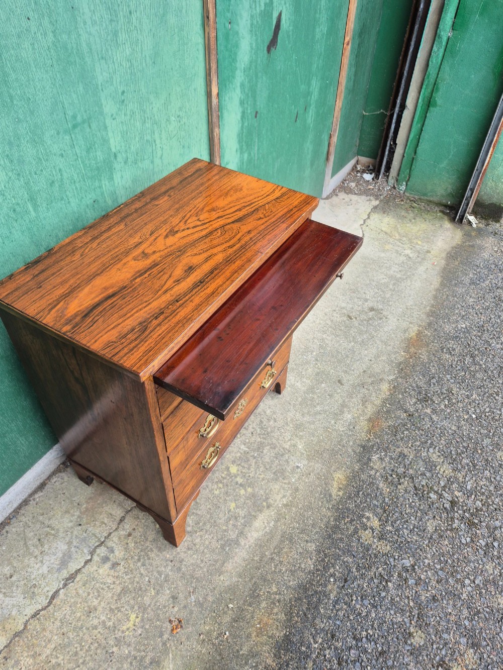 A small rosewood chest of drawers featuring brass handles, bracket feet, and a pull-out brushing slide. View IV