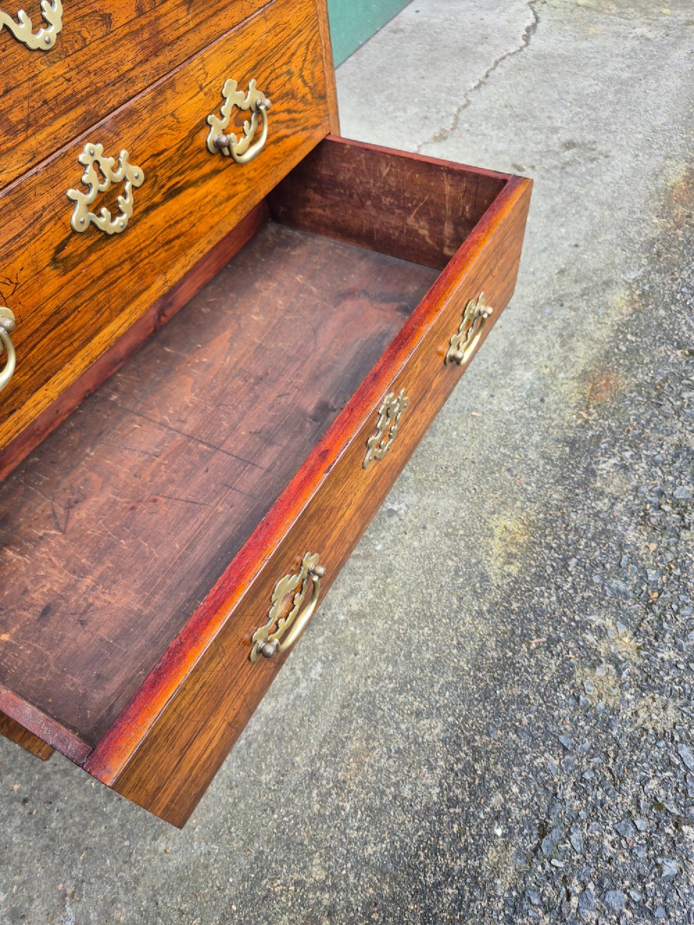 A small rosewood chest of drawers featuring brass handles, bracket feet, and a pull-out brushing slide. View V