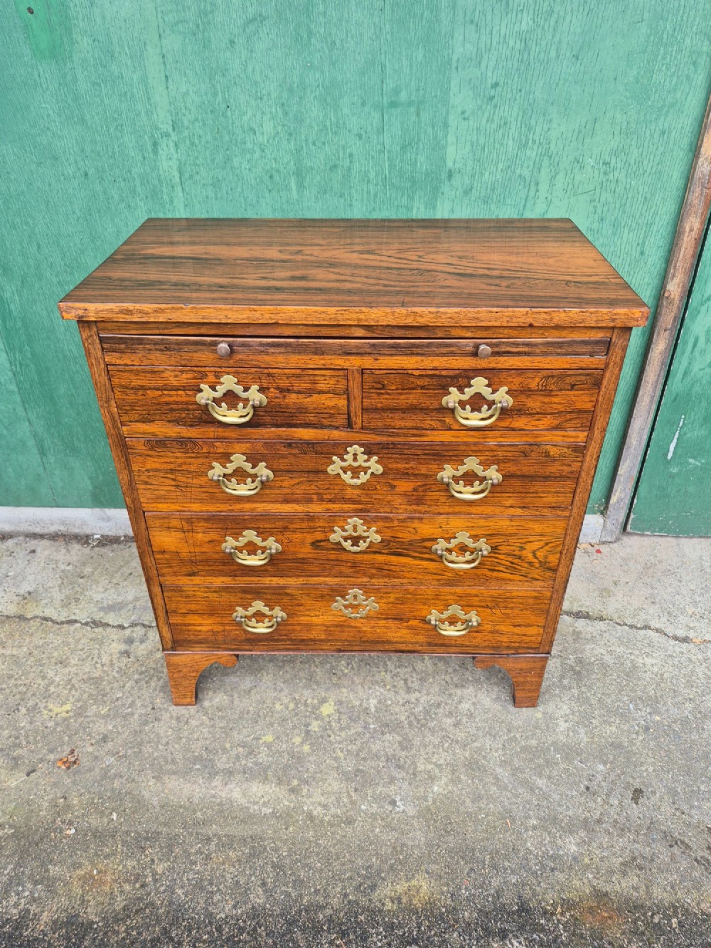 A small rosewood chest of drawers featuring brass handles, bracket feet, and a pull-out brushing slide. View XII