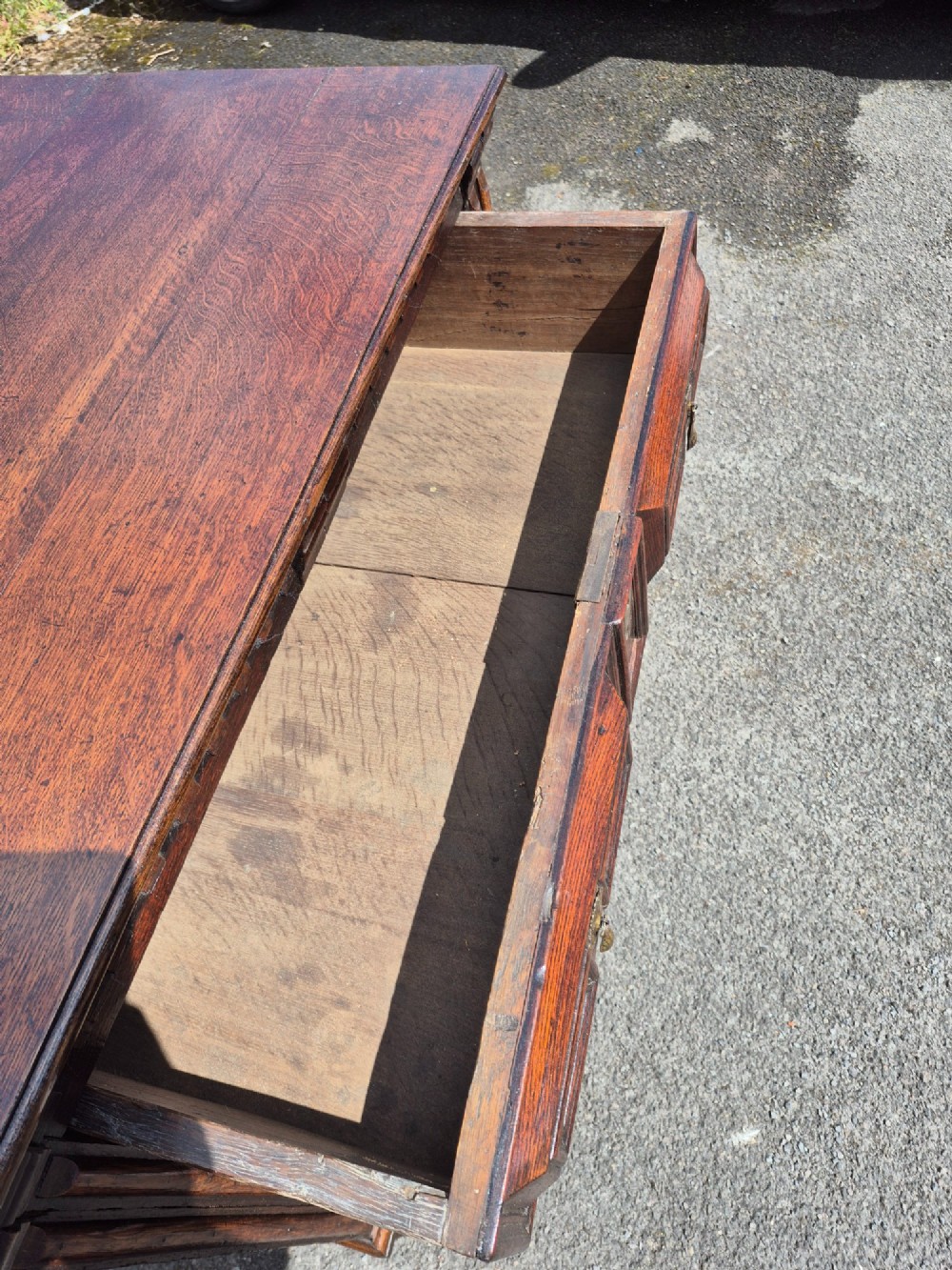 A dark oak chest of drawers featuring three drawers with geometric panel mouldings, brass drop handles, and turned bun feet. View VIII