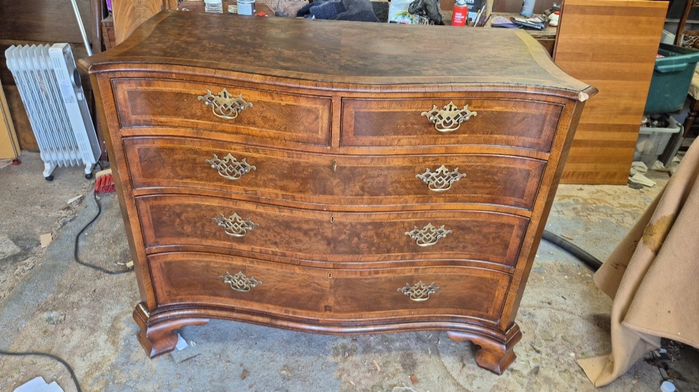 A burr walnut serpentine-front chest of drawers with two short top drawers over three long drawers, featuring brass backplate handles and resting on bracket feet. View XIV