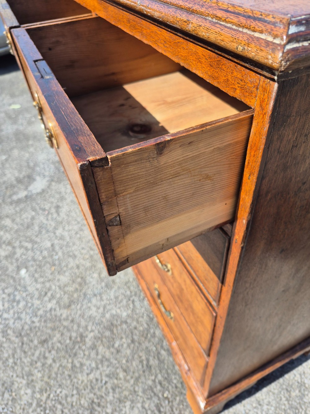 A Georgian golden oak chest of drawers with two short drawers over three long drawers, featuring brass handles and bracket feet. View VIII