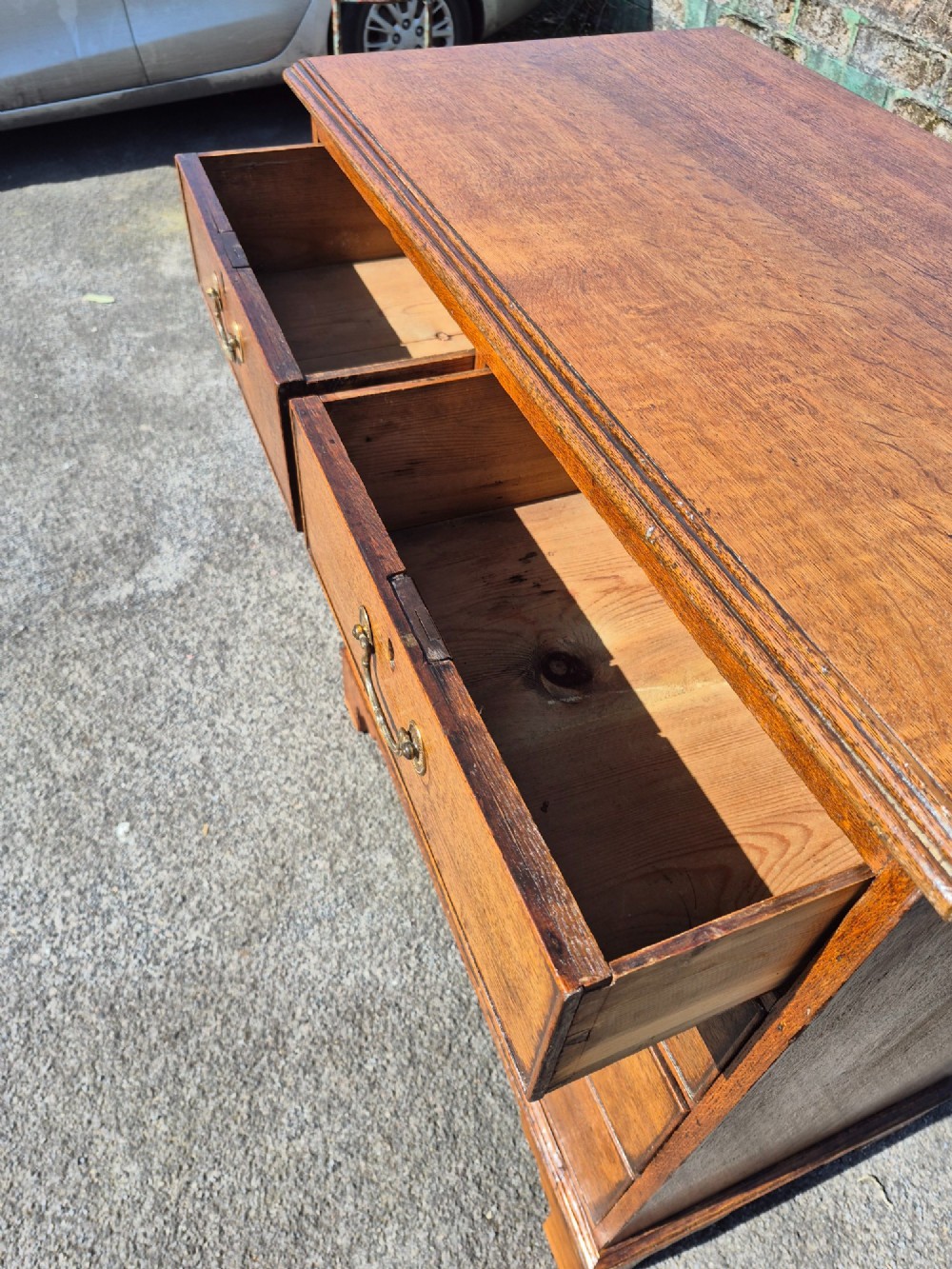 A Georgian golden oak chest of drawers with two short drawers over three long drawers, featuring brass handles and bracket feet. View IX