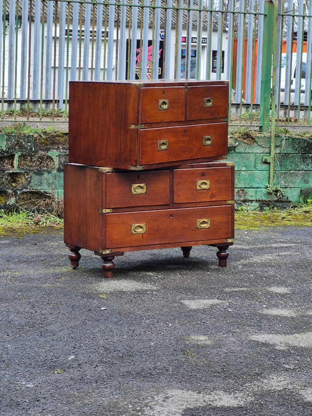 A nineteenth-century two-part mahogany military campaign chest featuring brass flush handles, protective brass corner mounts, and turned feet.