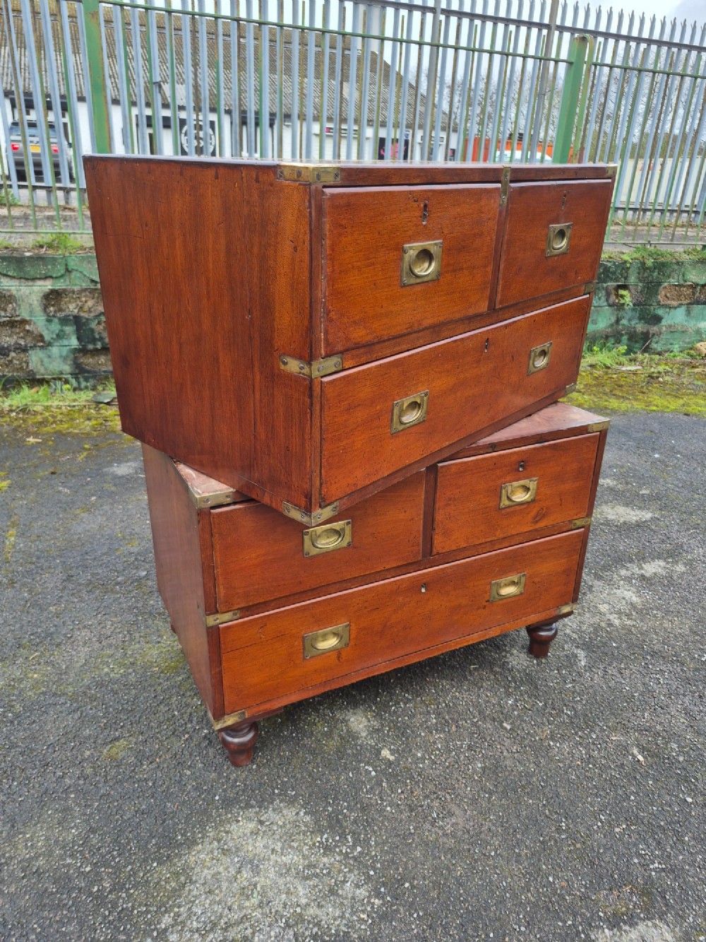 A nineteenth-century two-part mahogany military campaign chest featuring brass flush handles, protective brass corner mounts, and turned feet. View II