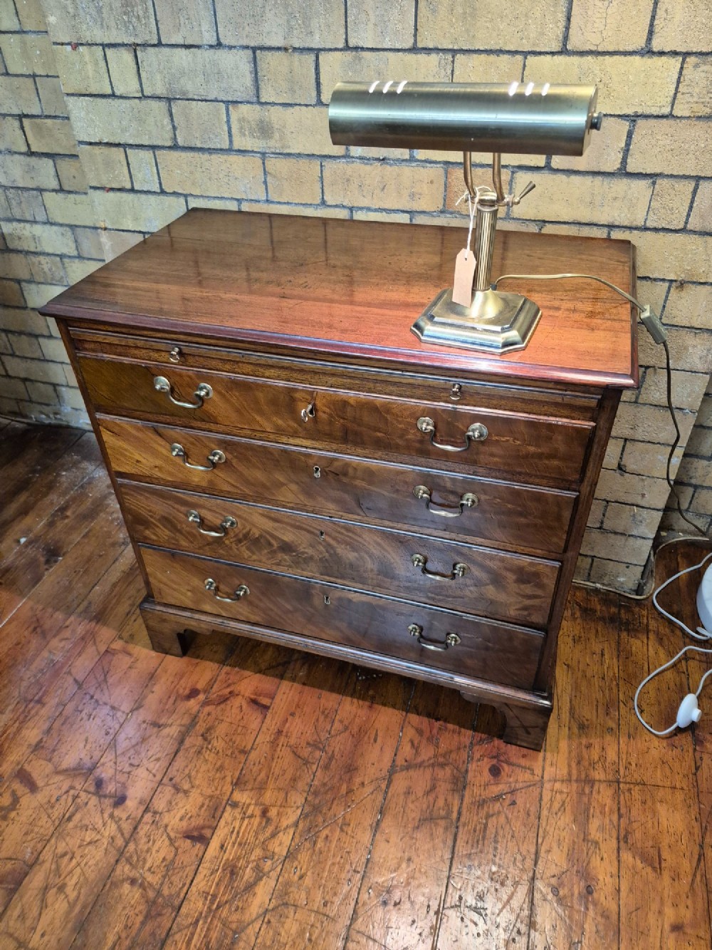 A Georgian mahogany bachelors chest featuring a top brushing slide, four graduated drawers with flame mahogany veneers, brass swan-neck handles, and bracket feet. View III