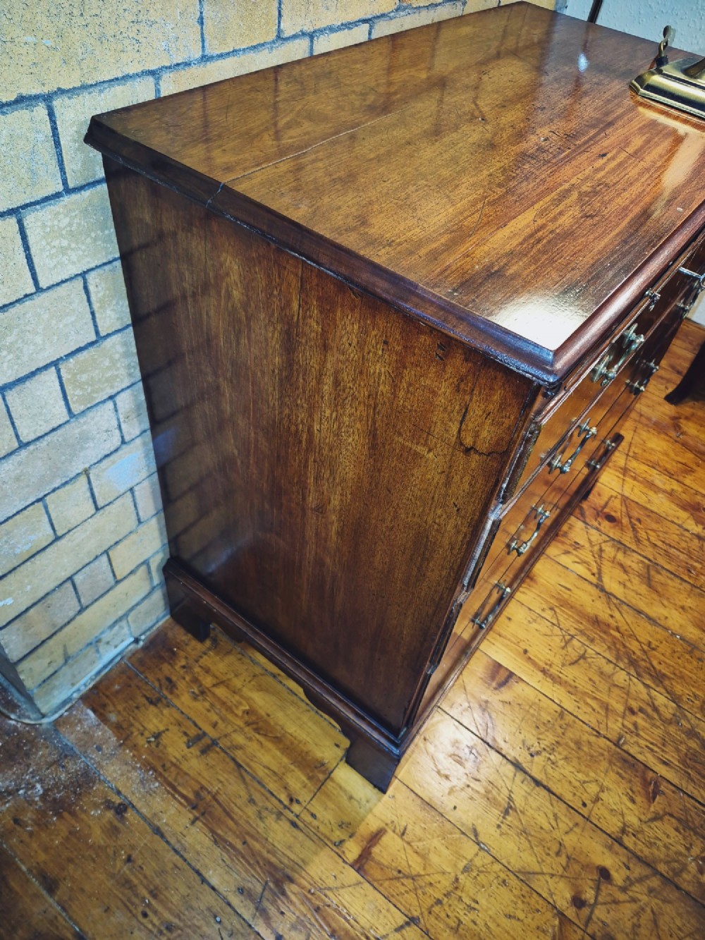 A Georgian mahogany bachelors chest featuring a top brushing slide, four graduated drawers with flame mahogany veneers, brass swan-neck handles, and bracket feet. View IX