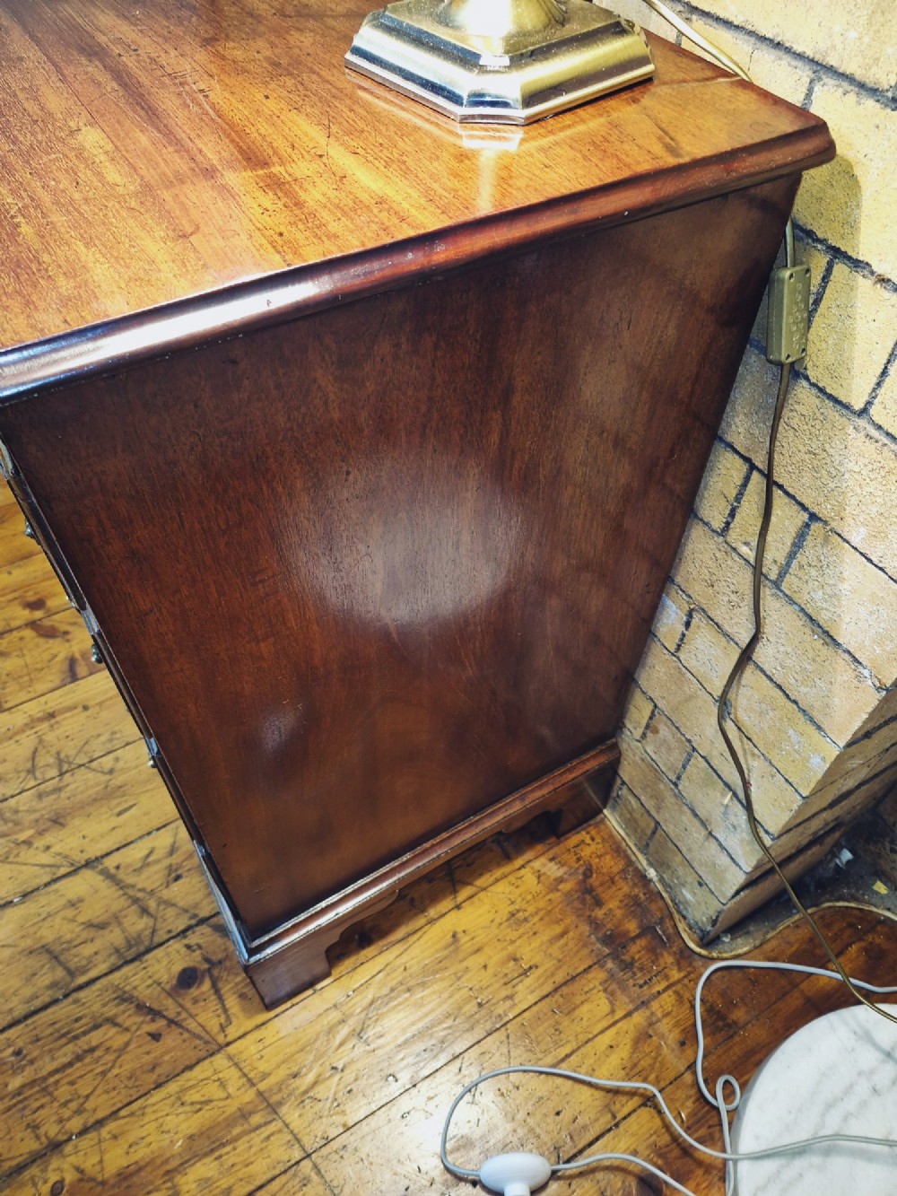 A Georgian mahogany bachelors chest featuring a top brushing slide, four graduated drawers with flame mahogany veneers, brass swan-neck handles, and bracket feet. View X