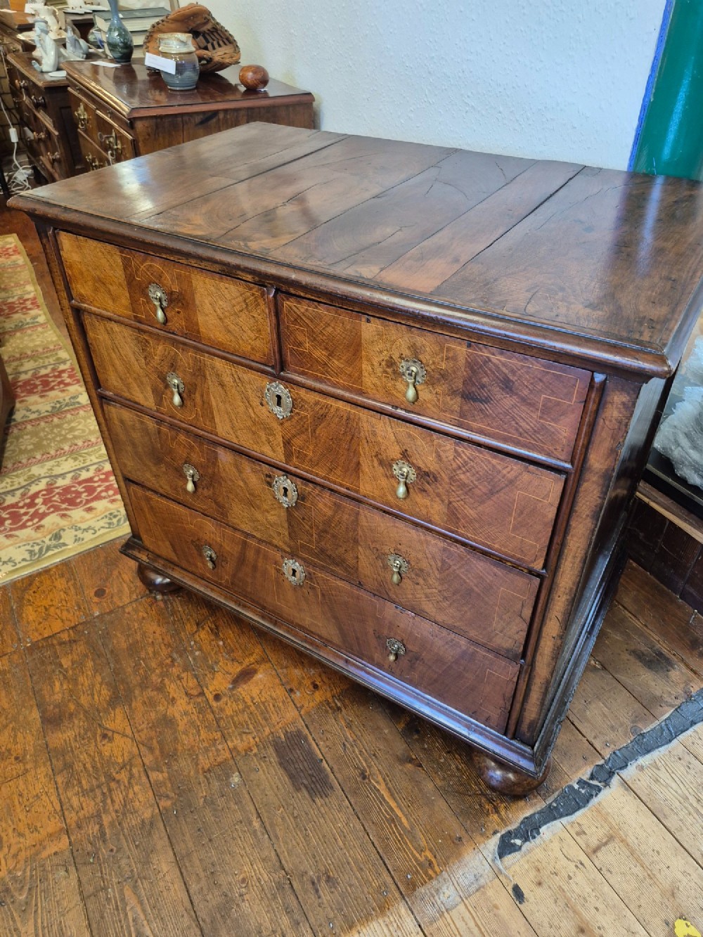 A William and Mary walnut chest of drawers featuring geometric crossbanded drawer fronts, brass drop handles, and compressed bun feet. View III