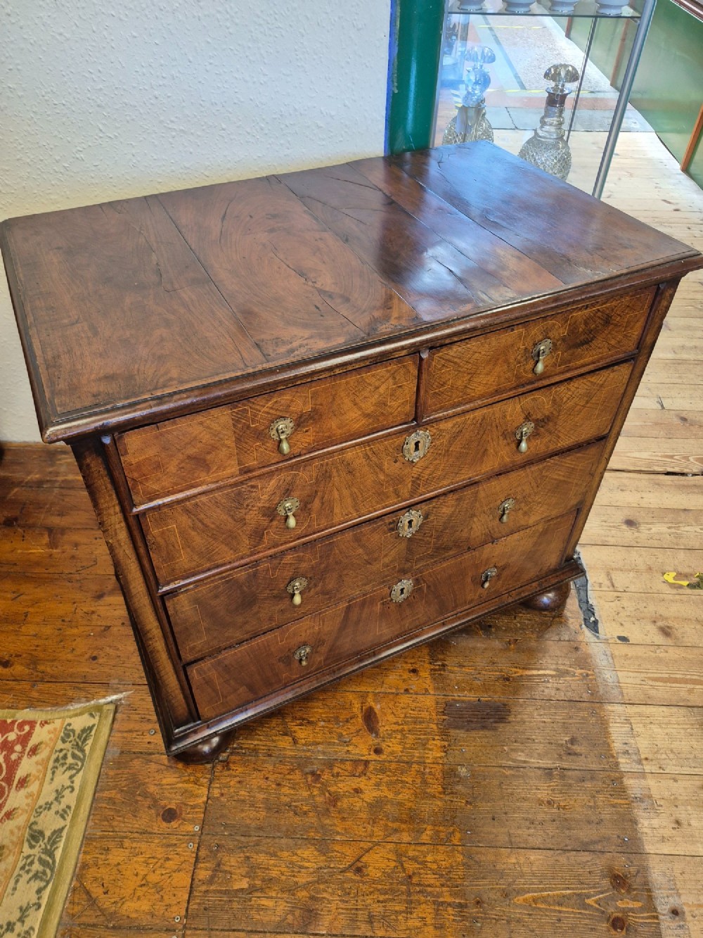 A William and Mary walnut chest of drawers featuring geometric crossbanded drawer fronts, brass drop handles, and compressed bun feet. View IV