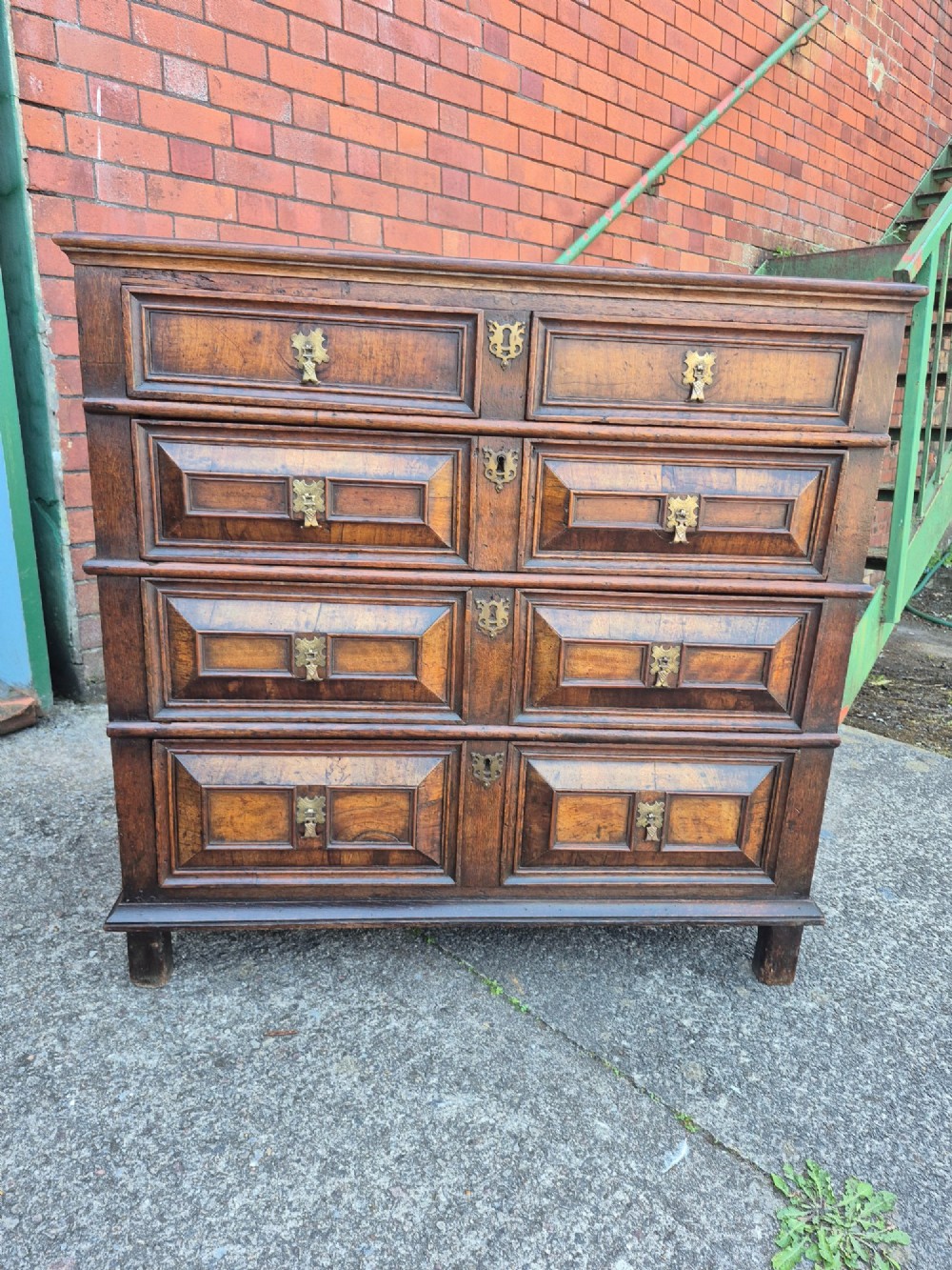 A seventeenth-century Charles II oak and walnut chest of drawers featuring four long drawers with raised geometric panel mouldings and brass drop handles.