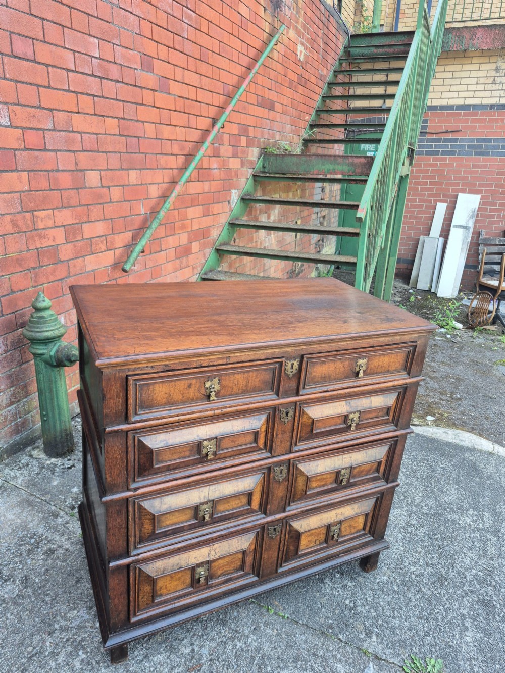 A seventeenth-century Charles II oak and walnut chest of drawers featuring four long drawers with raised geometric panel mouldings and brass drop handles. View III