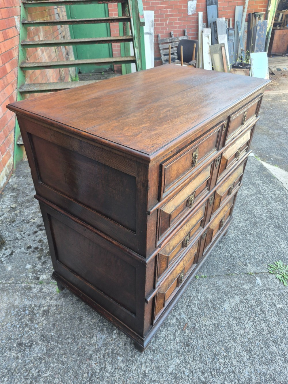 A seventeenth-century Charles II oak and walnut chest of drawers featuring four long drawers with raised geometric panel mouldings and brass drop handles. View IV