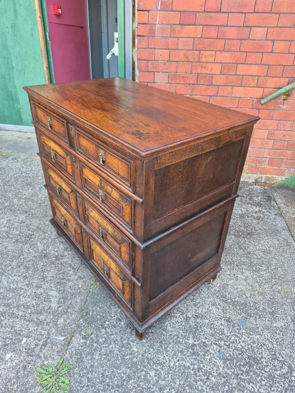 A seventeenth-century Charles II oak and walnut chest of drawers featuring four long drawers with raised geometric panel mouldings and brass drop handles. View V