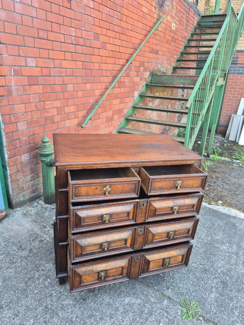 A seventeenth-century Charles II oak and walnut chest of drawers featuring four long drawers with raised geometric panel mouldings and brass drop handles. View VI
