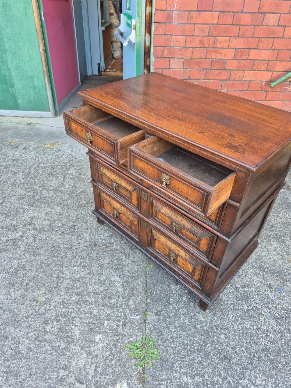 A seventeenth-century Charles II oak and walnut chest of drawers featuring four long drawers with raised geometric panel mouldings and brass drop handles. View VII