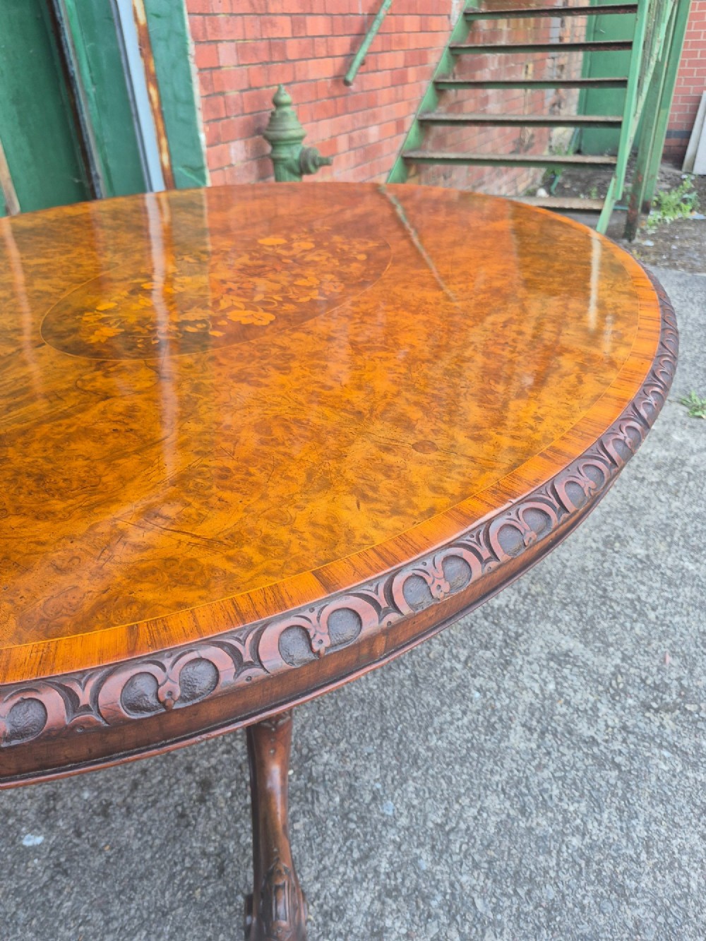 A Victorian oval burr walnut breakfast table with floral marquetry inlay, carved apron, and four carved cabriole legs. View III