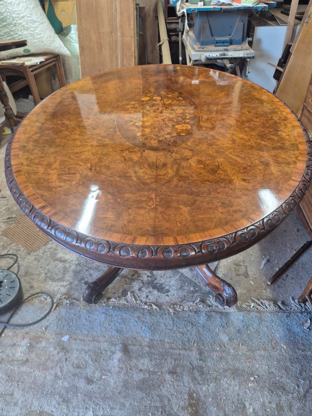 A Victorian oval burr walnut breakfast table with floral marquetry inlay, carved apron, and four carved cabriole legs. View XIII