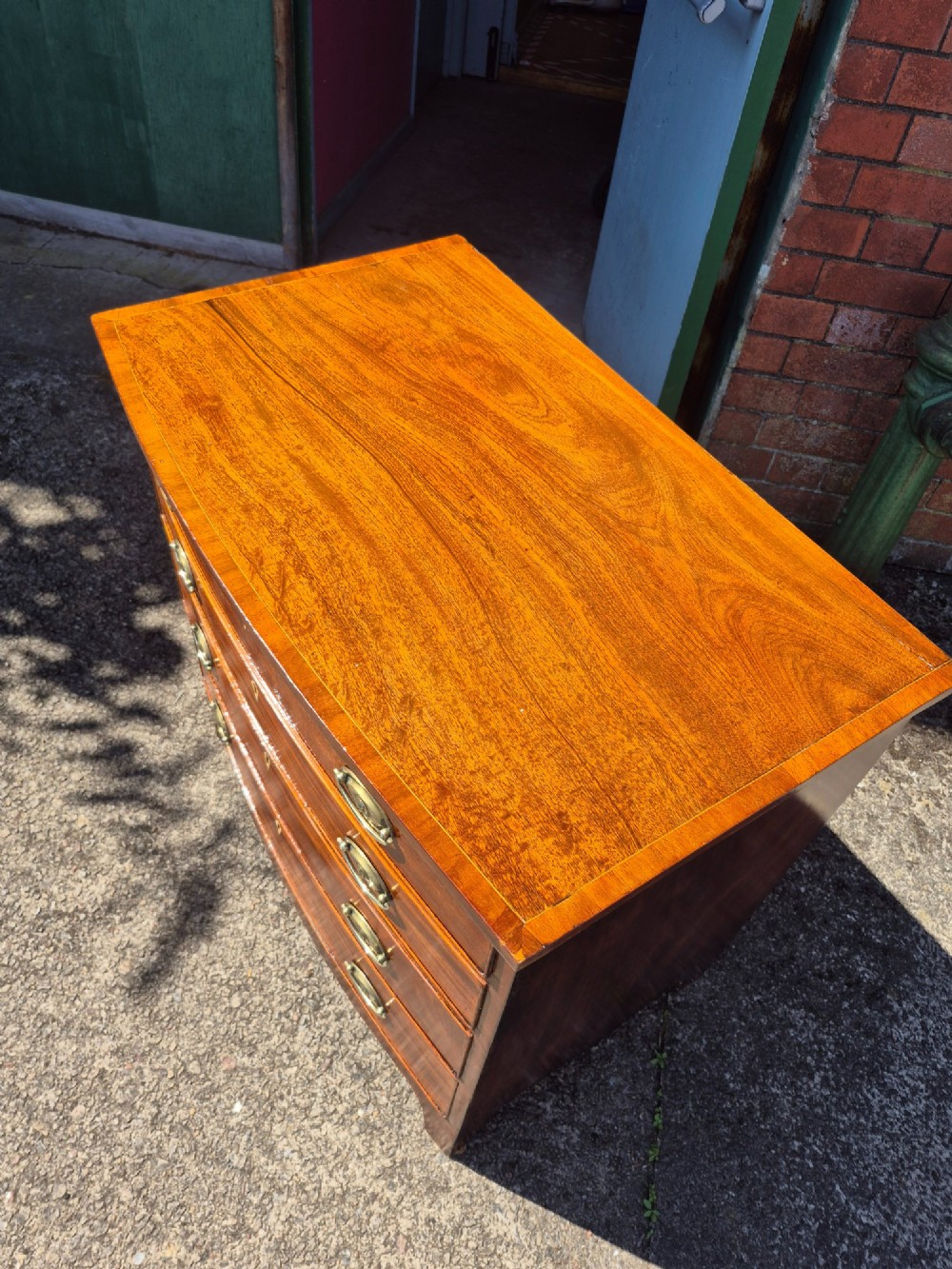 A Regency period mahogany bowfront chest featuring four graduated drawers with oval brass handles and splayed bracket feet. View XIII